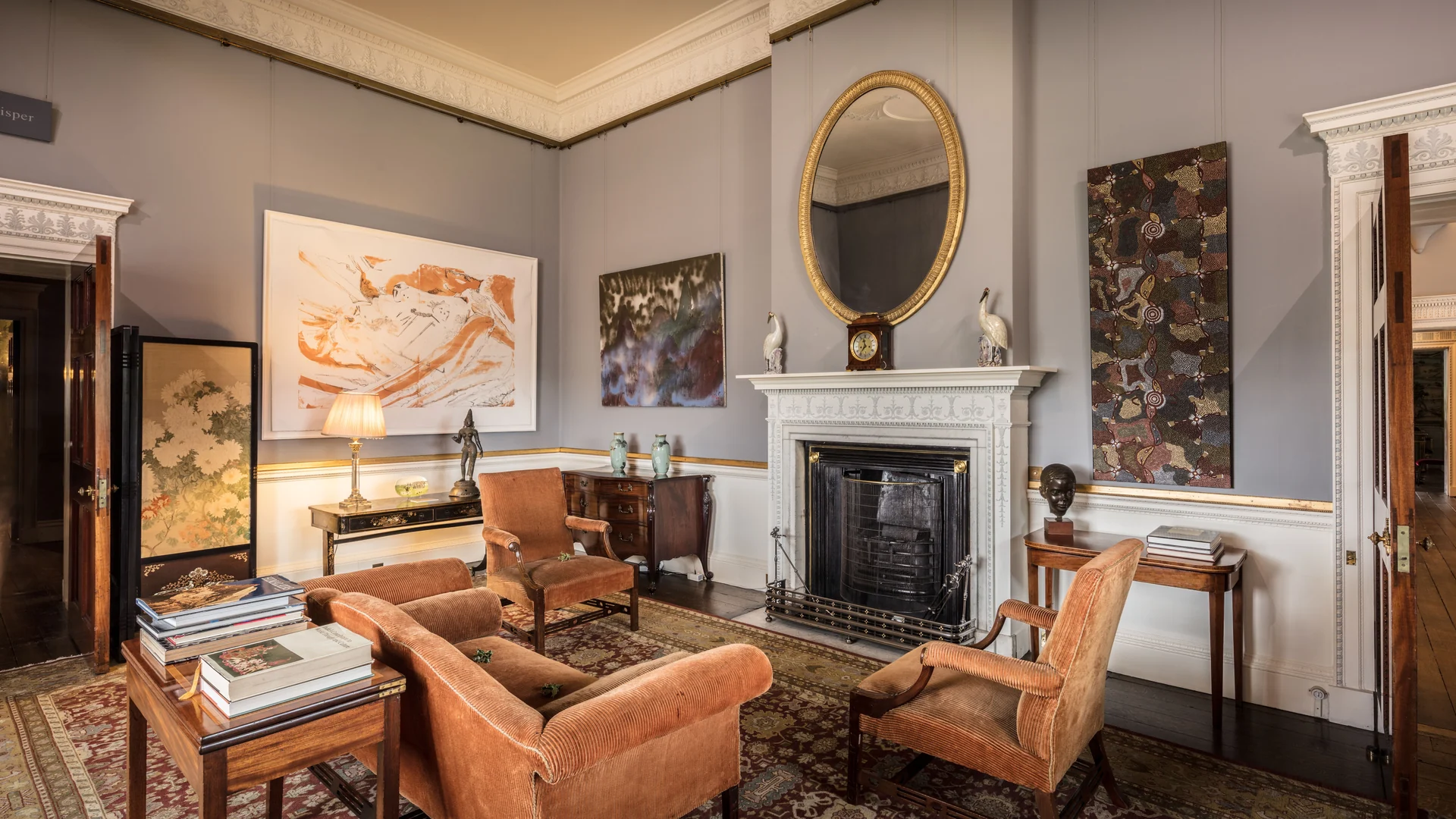 The drawing room, with a white marble chimneypiece and a gilt oval mirror