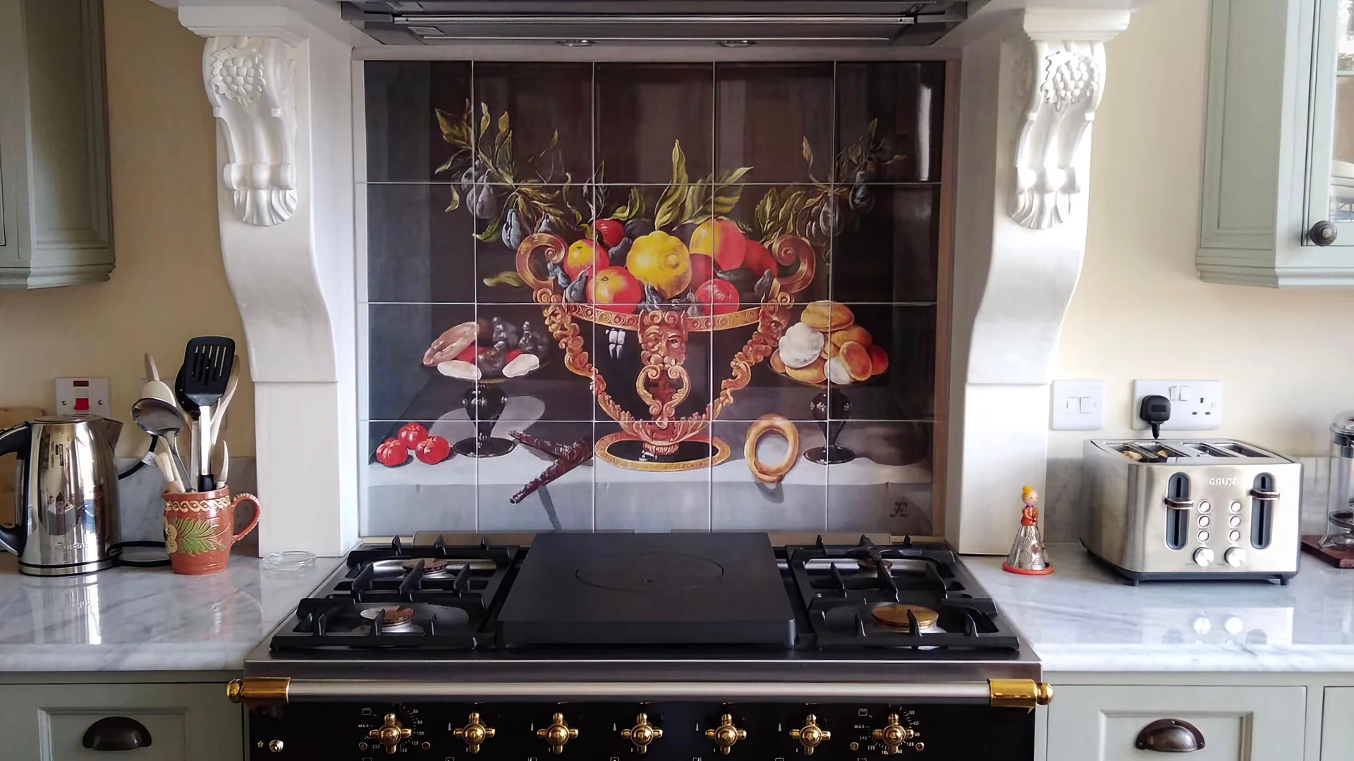 The kitchen at Wraycombe House, with a range cooker set under a painted hood and a hand-painted tiled panel